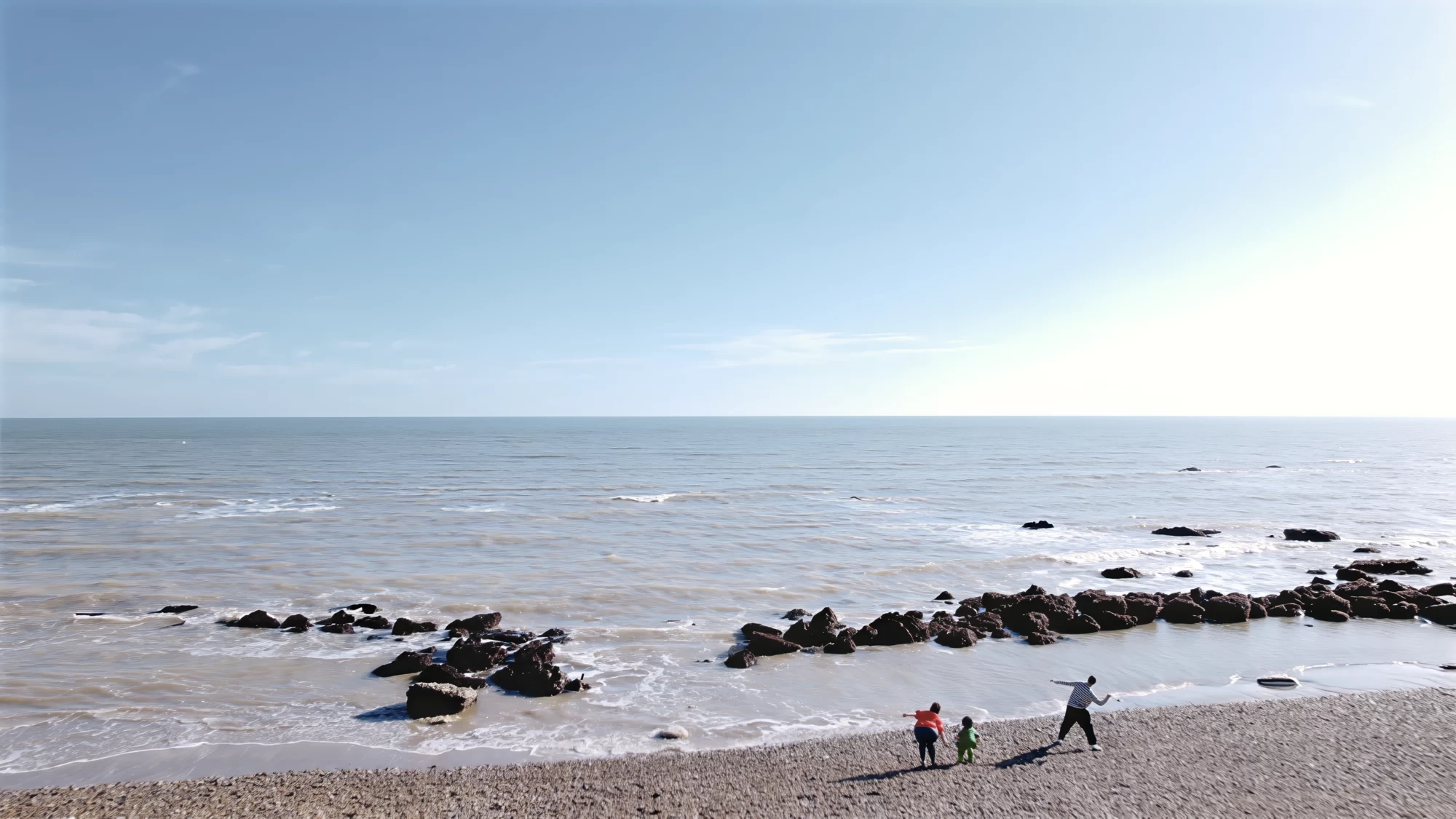 Visit Kent tourism photography — aerial view of a family walking the rocky shoreline