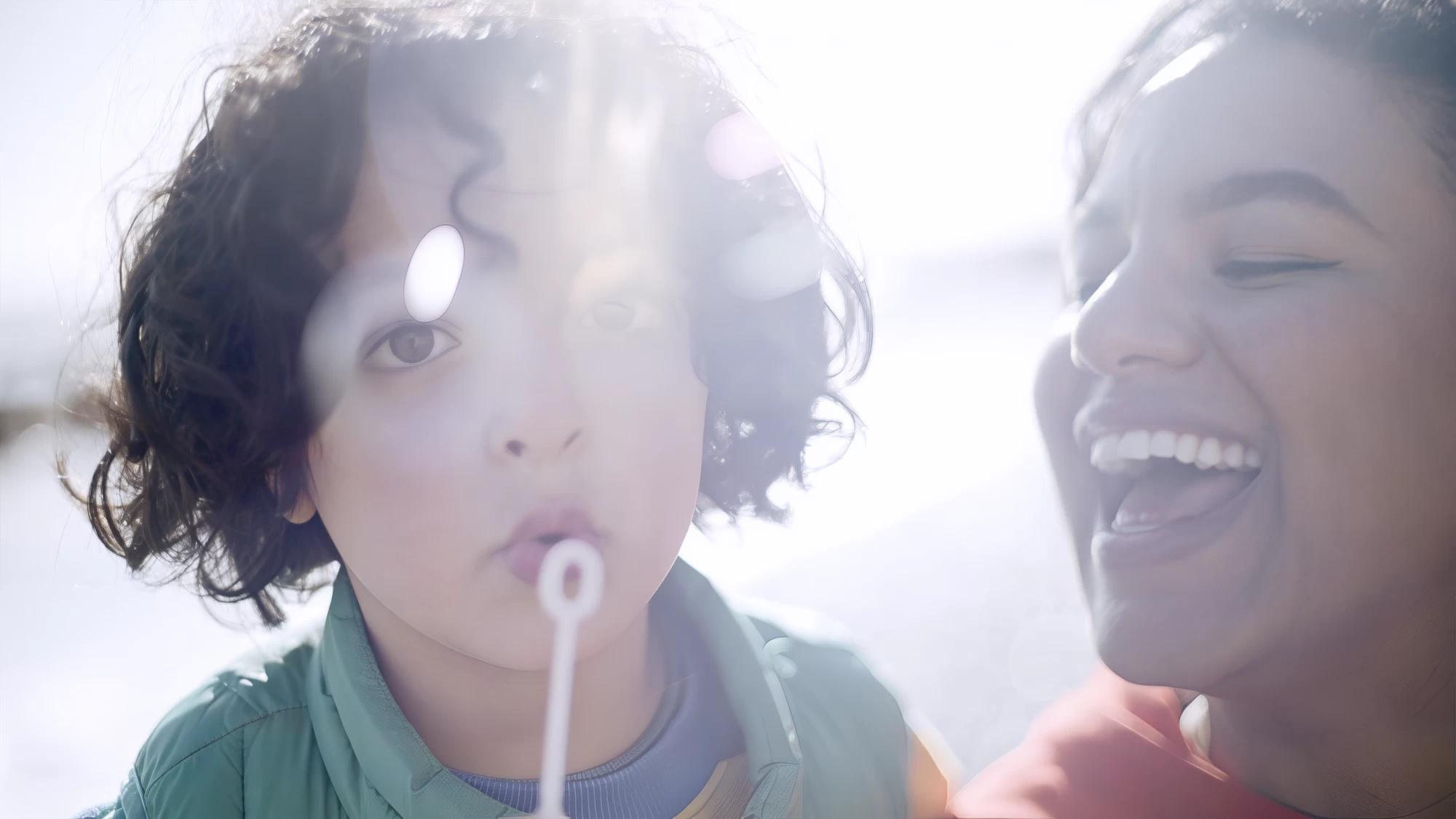 Visit Kent tourism photography — child blowing bubbles with a laughing parent on the coast