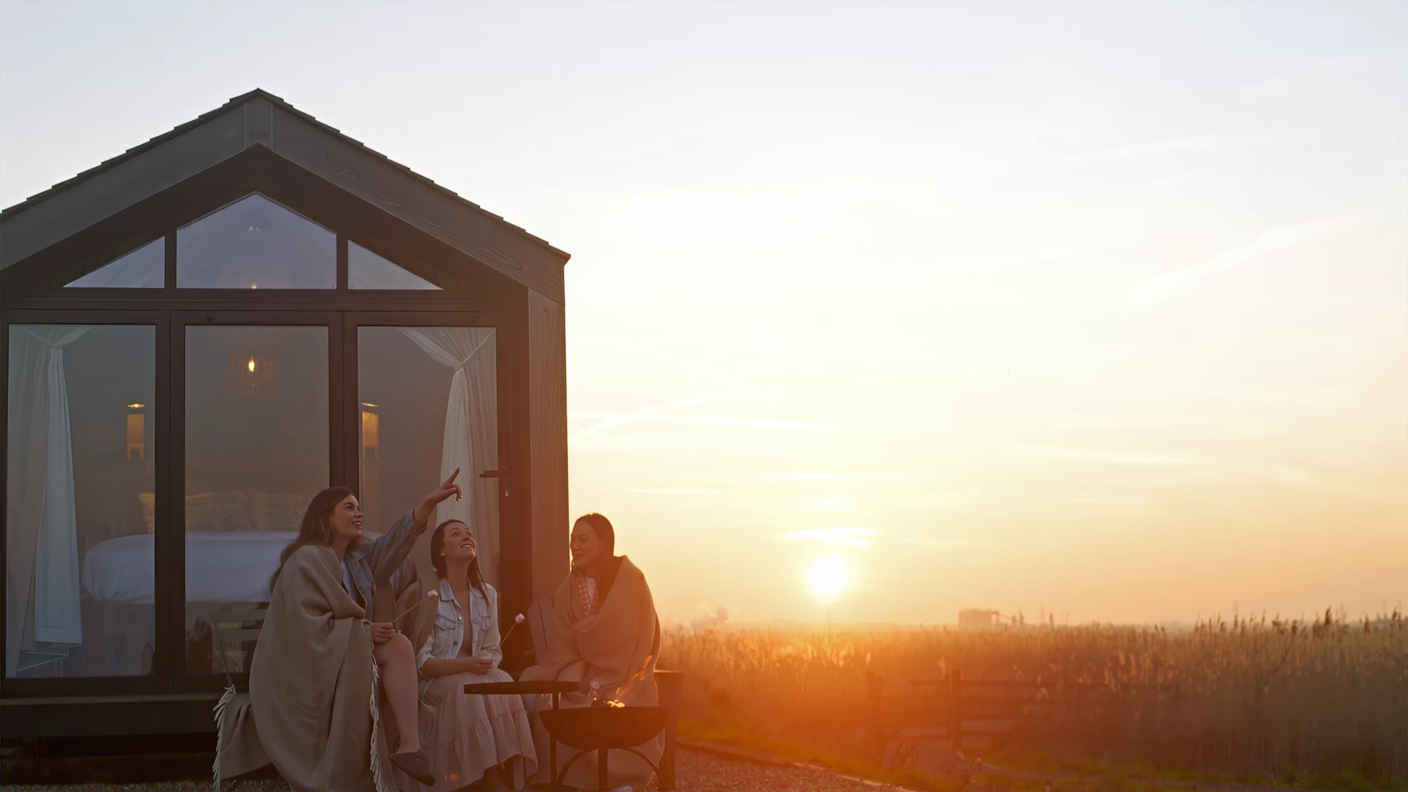 Visit Kent tourism photography — friends toasting marshmallows outside a shepherd's hut at sunset