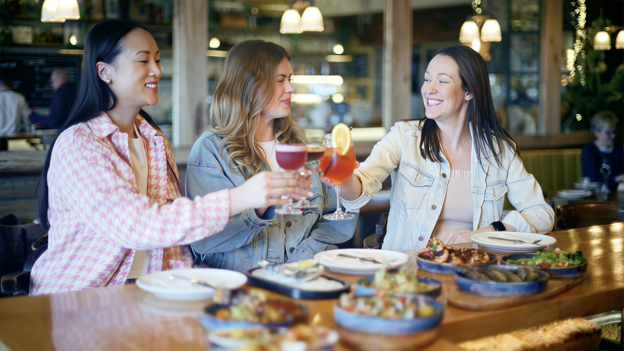 Visit Kent tourism photography — friends toasting cocktails over a seafood sharing table